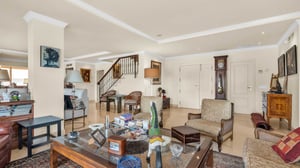 Another angle of the living area with classic furniture, books, decorative objects, and a grandfather clock, illustrating the home’s warm and eclectic design.