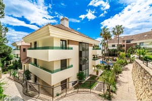 Modern luxury apartment complex in Marbella with lush tropical landscaping and pool view