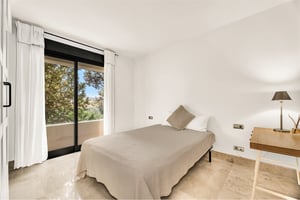 Cozy guest bedroom with desk and natural light overlooking trees in Marbella property