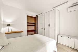 Stylish bedroom with white built-in closet and open shelving in contemporary apartment