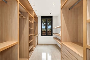 Spacious walk-in closet with custom wooden shelving and garden view window