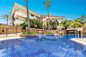 Resort-style swimming pool surrounded by palm trees and tropical landscaping in luxury complex