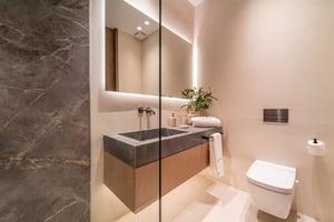 Compact modern bathroom with a stone sink, wall-mounted faucet, large mirror, and soft ambient lighting.