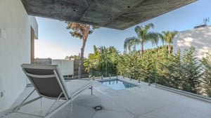 Terrace with a reclining sunbed, small private plunge pool, glass railing, and views of tropical greenery and tall trees.